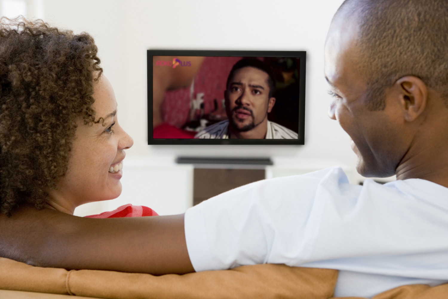 Couple in living room watching television smiling